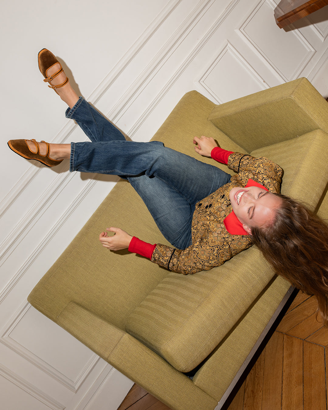 Overhead view of a woman on a sofa wearing the Nocciola Double Mary Jane with jeans and a printed jacket