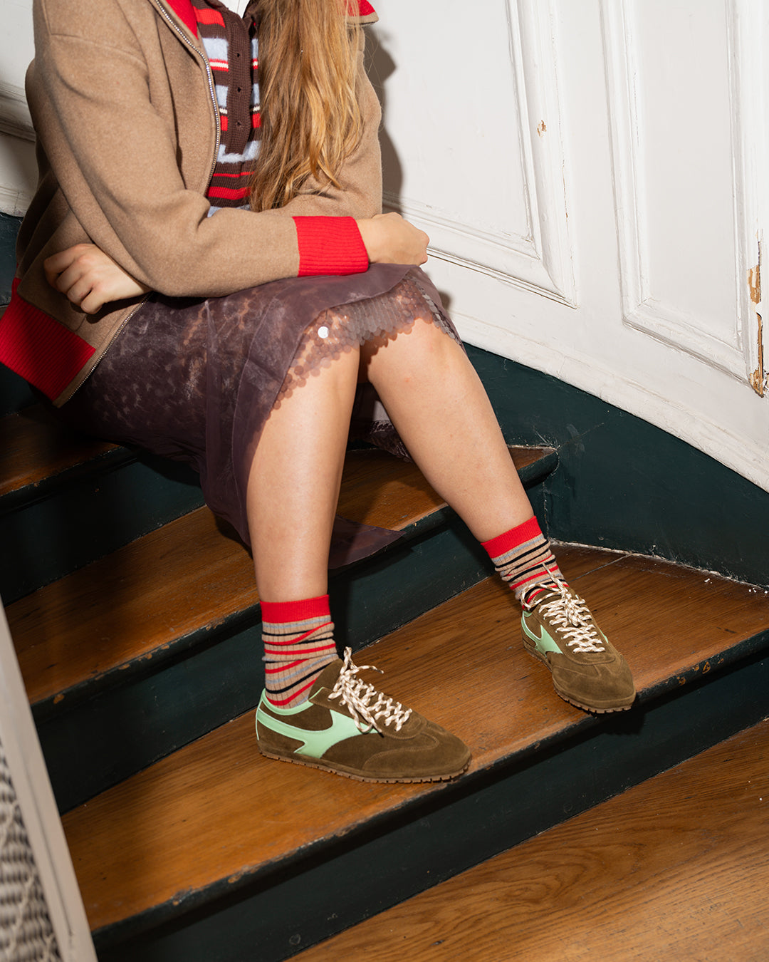 Sanremo Corsa Sneaker in olive suede and mint leather, worn with red striped socks on wooden stairs
