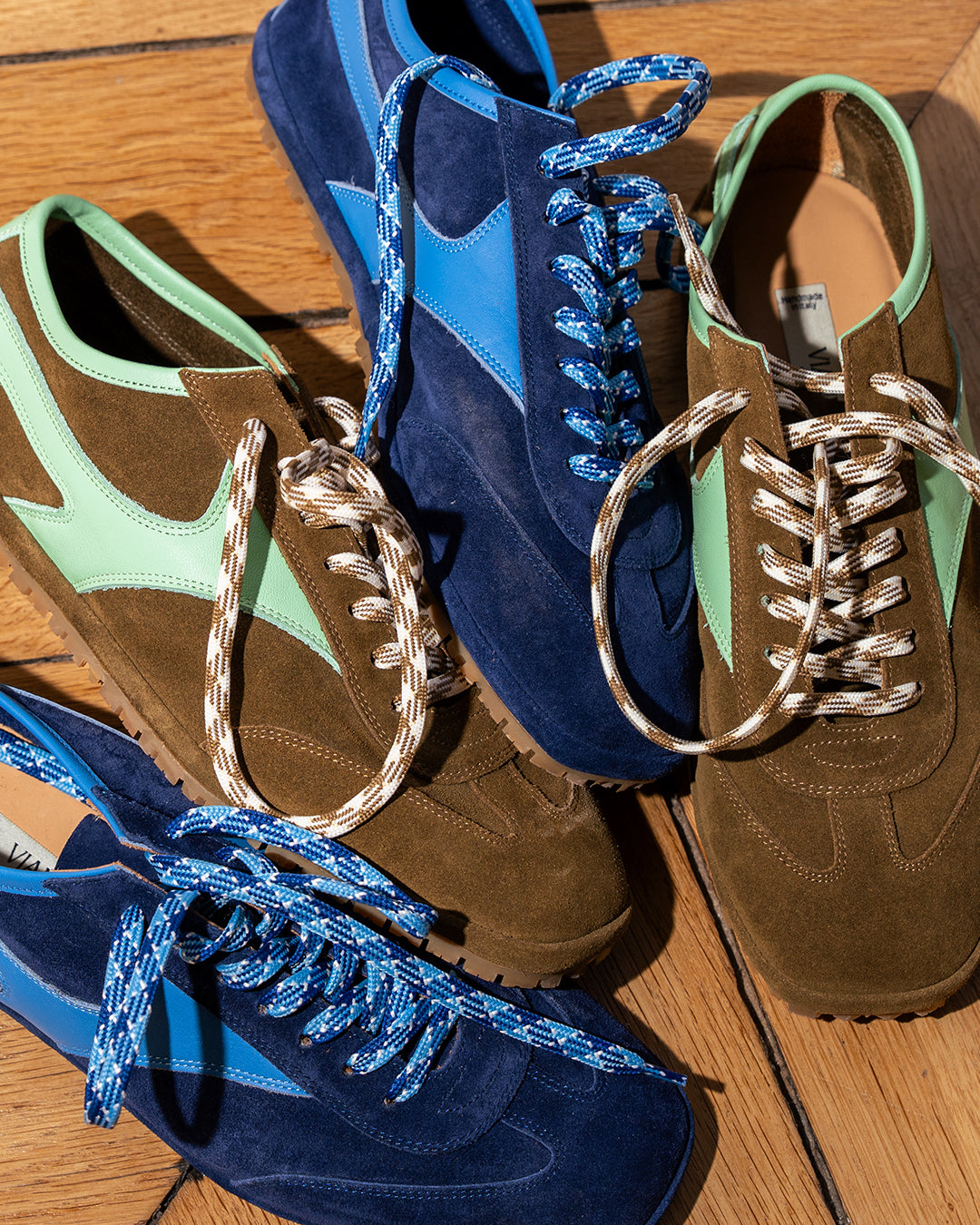 Sanremo Corsa Sneaker next to the Trieste Corsa Sneaker in navy suede on a wooden floor