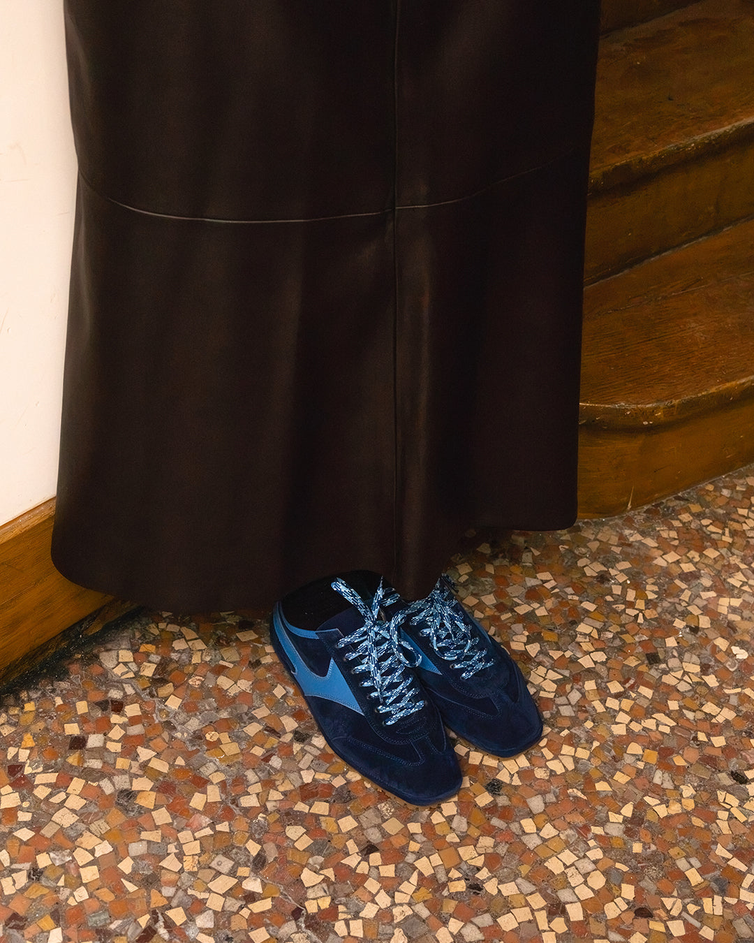Trieste Corsa Sneaker in navy suede worn with a long leather skirt on a terrazzo floor